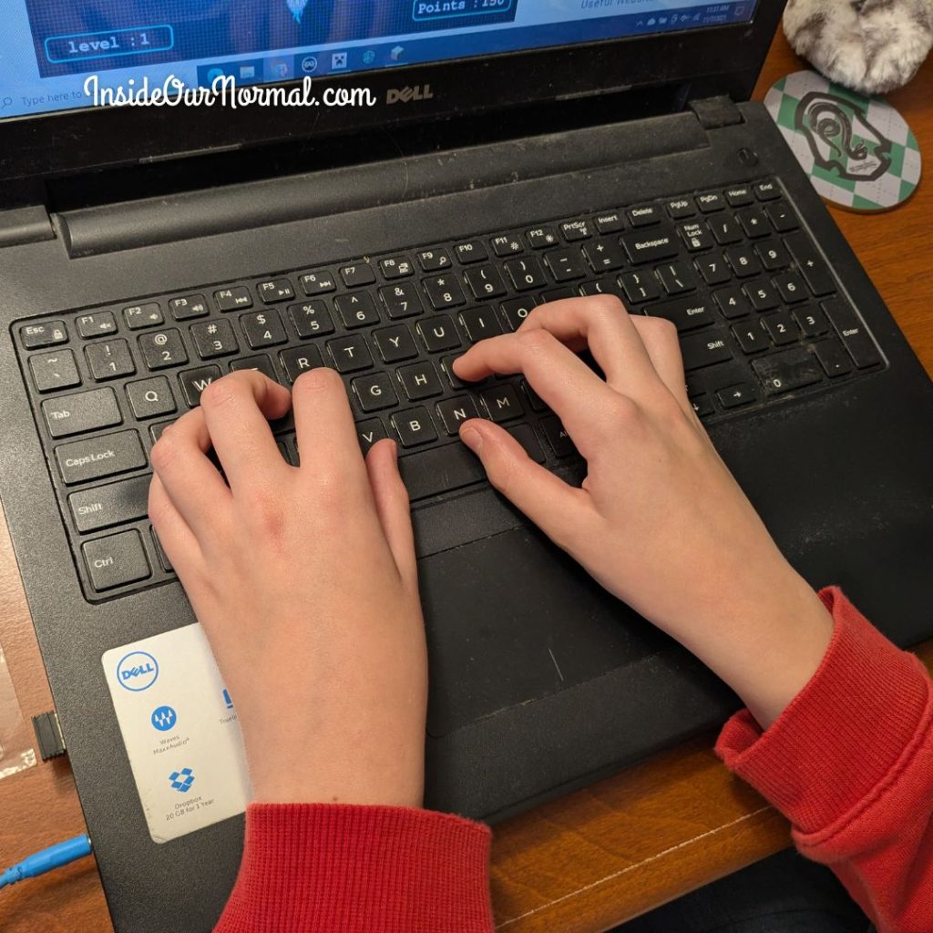 Close-up of a child’s hands typing on a colorful keyboard — practicing fine motor skills with KidzType typing games during homeschool lessons.